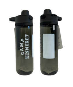 Two black water bottles with "CAMP KINNERET" printed on one side, featuring flip-top lids and carry handles. A white label is on the left side of both bottles.